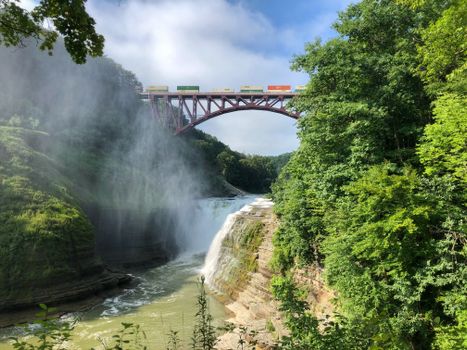 Scenic view of a waterfall and train bridge at Letchworth State Park, NY.