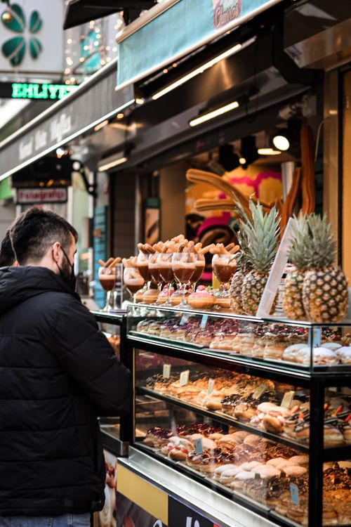 Free Man browsing a food stall in Istanbul with a display of pastries and fresh pineapples. Stock Photo