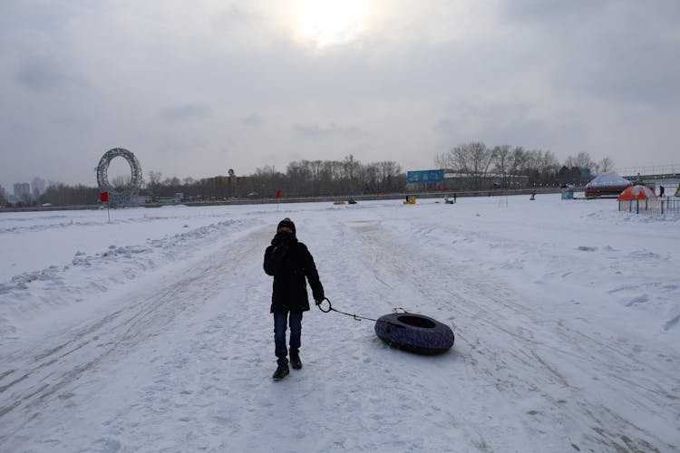 A Kid Dragging A Snow Tube