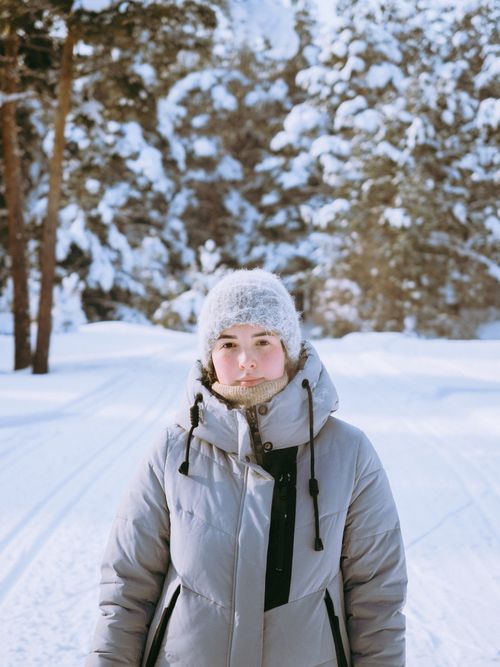 Free A woman in a beanie and jacket poses in a snowy forest, capturing the essence of winter. Stock Photo