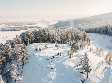 A stunning aerial view of a snow-covered forest landscape with people enjoying the peaceful winter scenery.