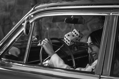 Free Smiling woman enjoying a drive in a vintage car with fuzzy dice, exuding a retro feel. Stock Photo