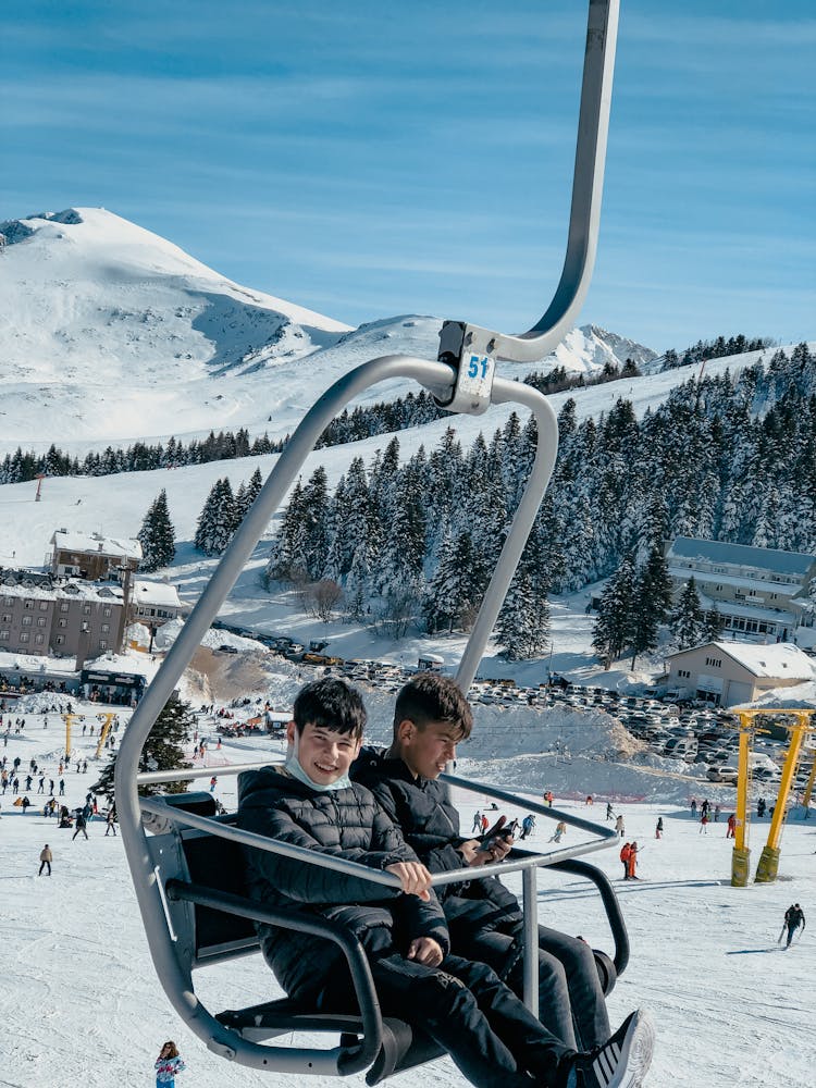 Two Boys On Ski Lift Chair In Winter Resort