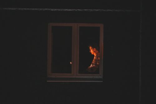 Free Silhouetted man working late at night in quiet solitude by window light. Stock Photo