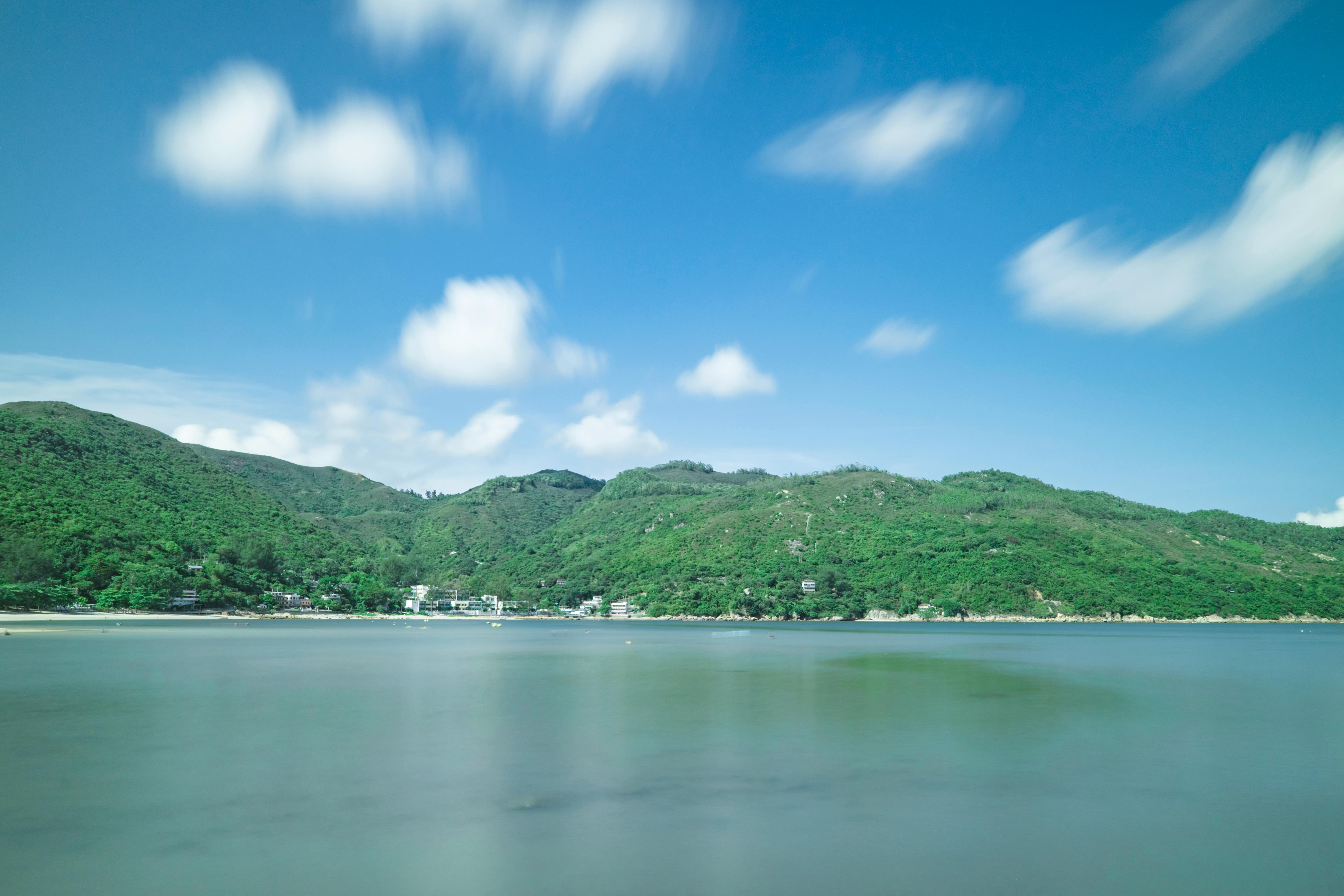 美丽的沿海景观中，郁郁葱葱的青山与平静的大海相映成趣，明亮的蓝天与云层交相辉映