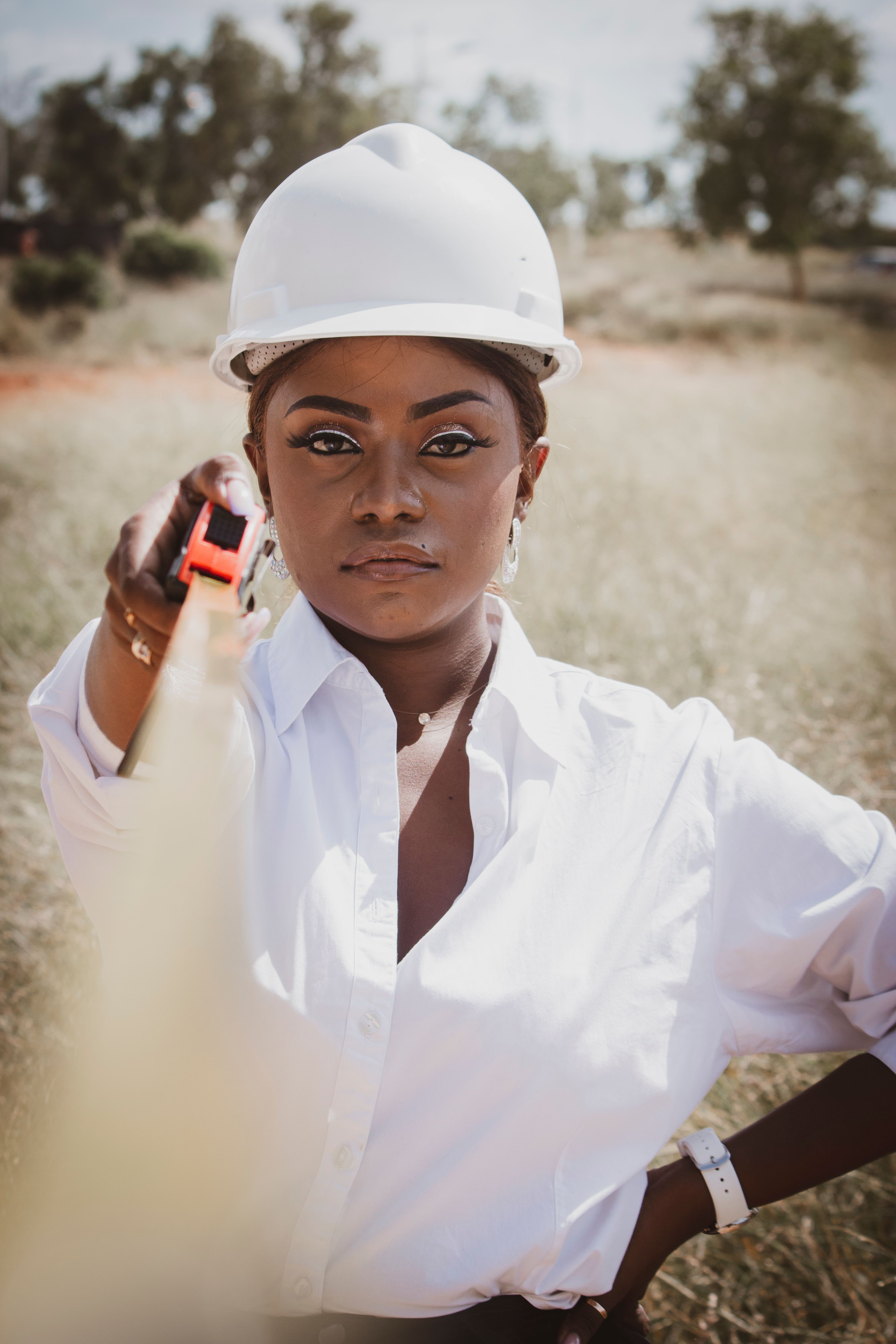 A focused female engineer with a tape measure and helmet outdoors, embodying empowerment and precision.