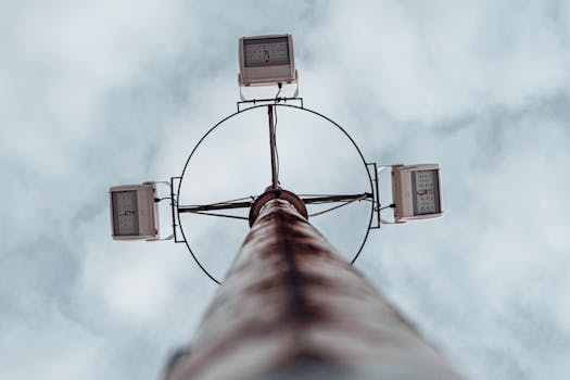 Dramatic low angle shot of a high mast lighting pole against an overcast sky.