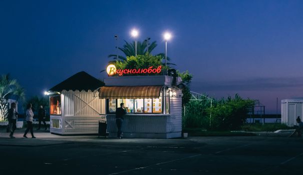 Evening view of a lit café stand in Sochi against a twilight sky.