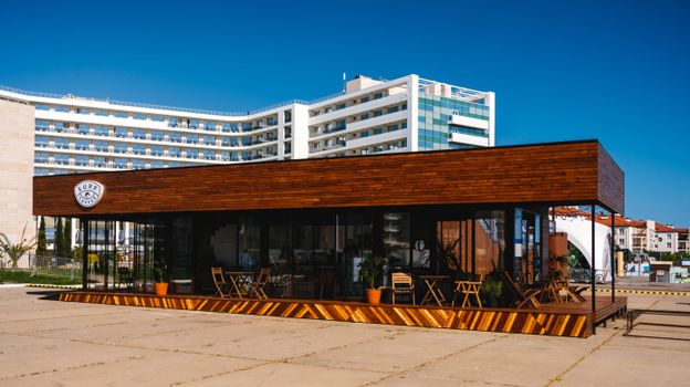 Contemporary café with wooden facade and outdoor seating in Sochi, Russia.
