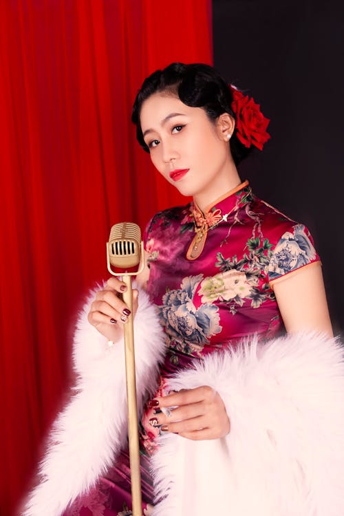 Free Woman in Traditional Dress and Fur Coat Holding a Microphone while Looking at the Camera Stock Photo