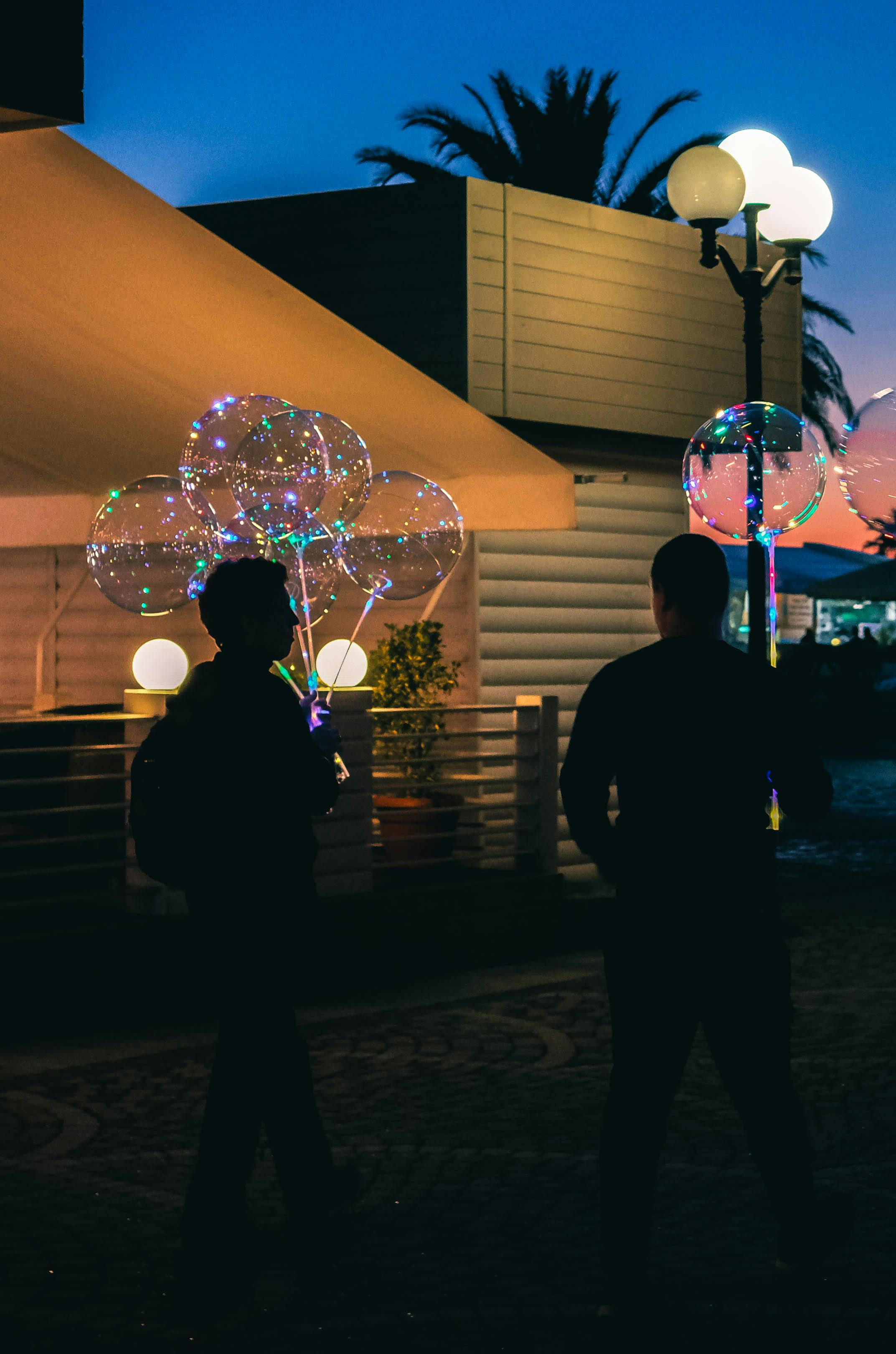 Two men holding balloons. | Photo: Pexels