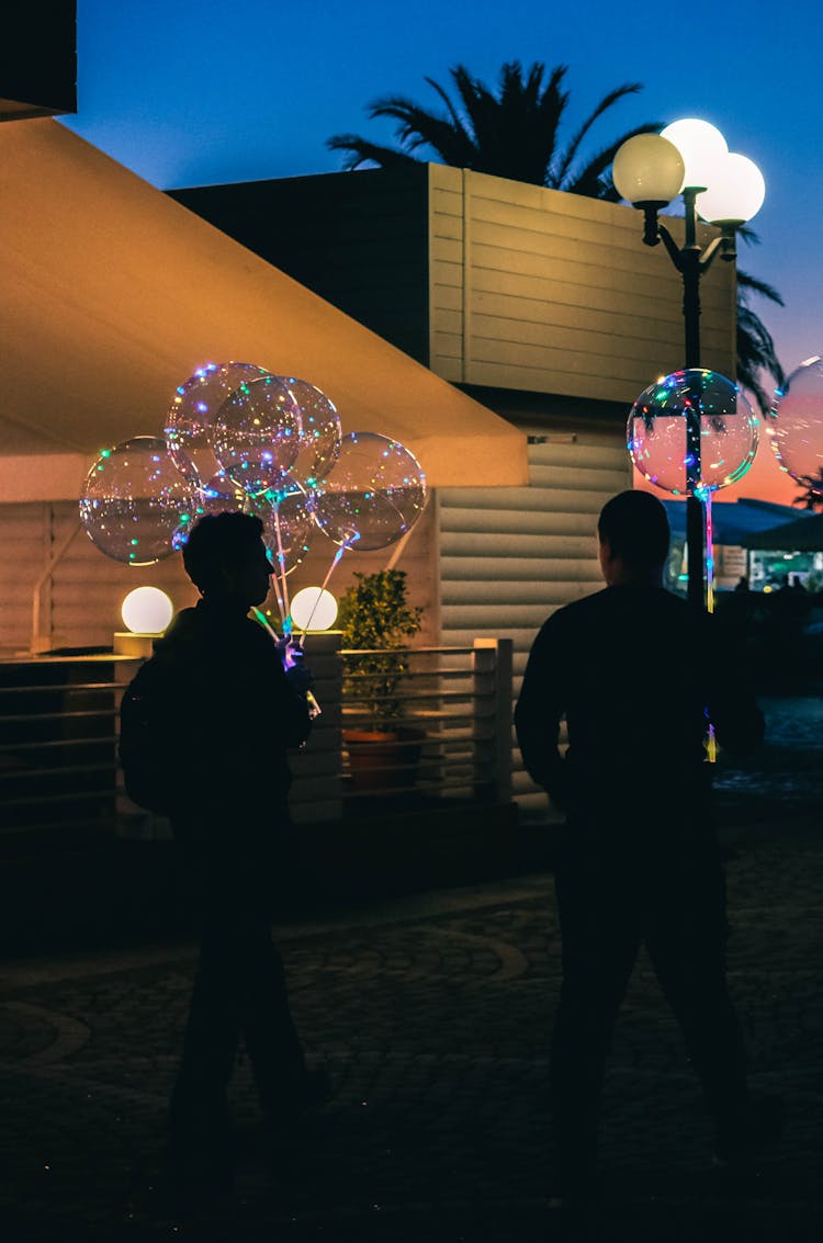 Silhouette Of Two People Holding Bubble Balloons