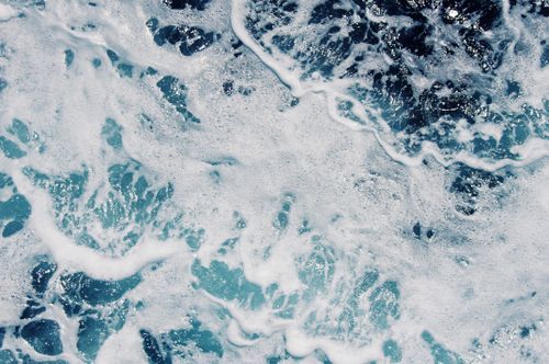 Free Detailed close-up of ocean waves with foamy white splash and deep blue water texture. Stock Photo