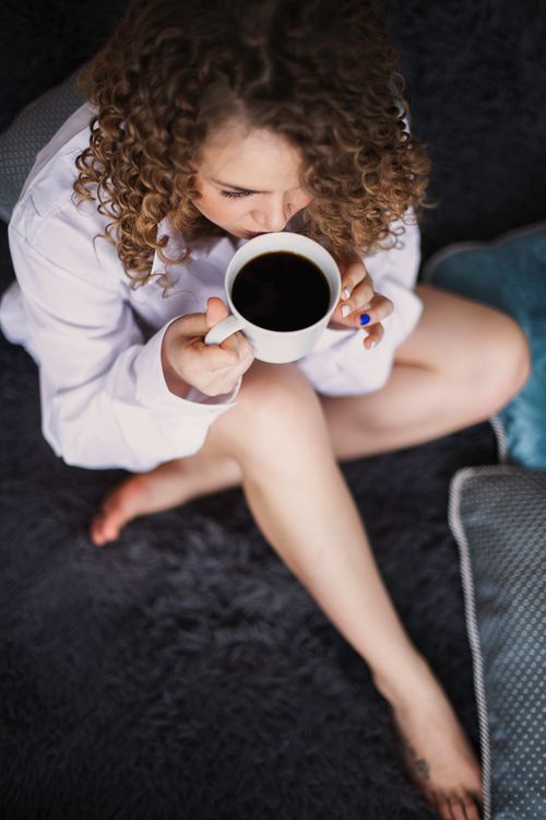 Free Woman enjoying a warm coffee, captured from above, adding a cozy and relaxed vibe. Stock Photo