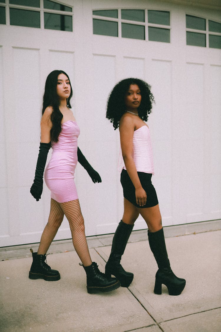 Women In Pink And Black Outfits Walking Down Street