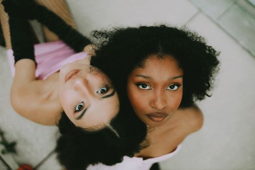A captivating portrait of two women with diverse backgrounds looking up at the camera.