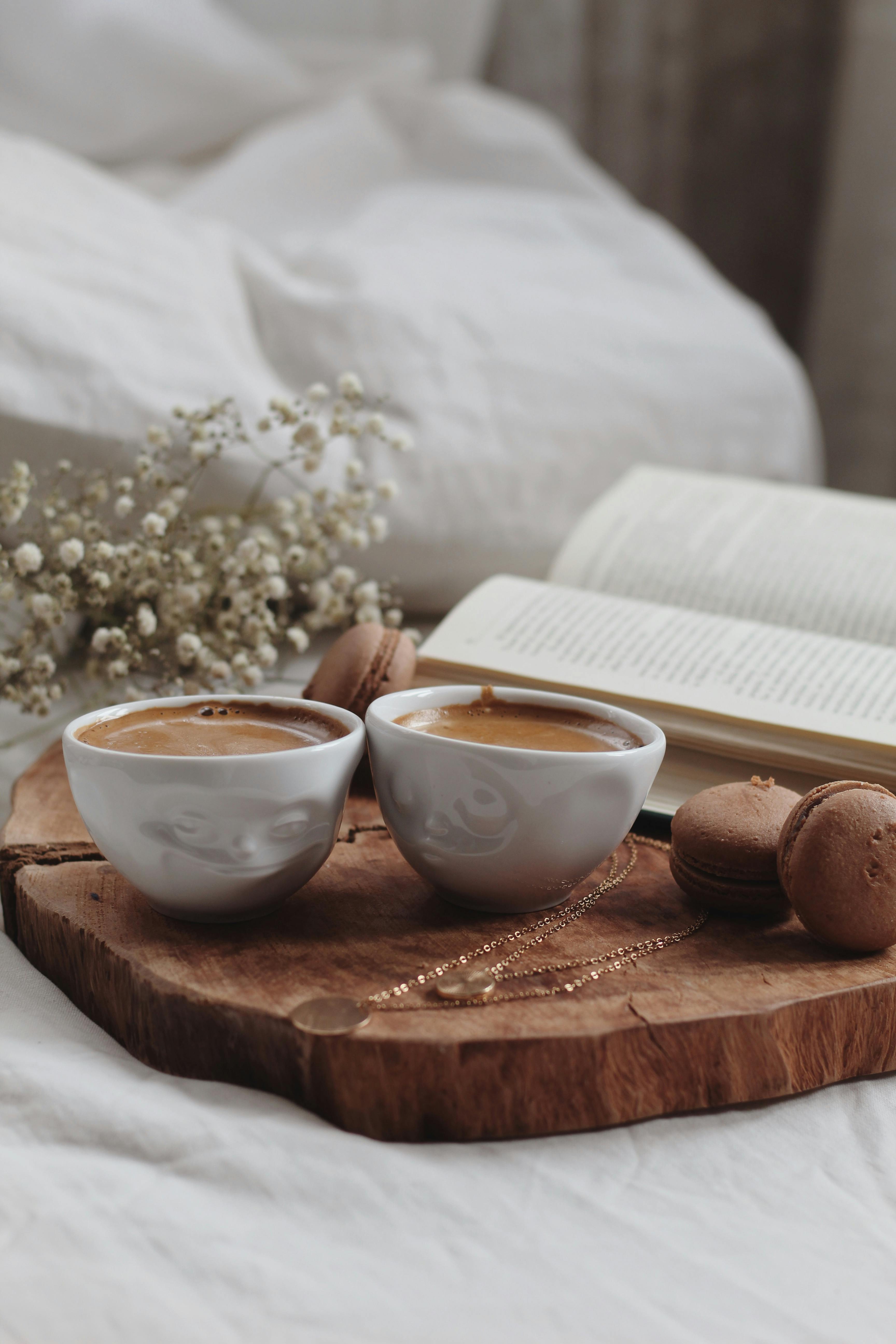 Warm coffee cups, cookies, and a book create a cozy atmosphere for relaxing indoors.