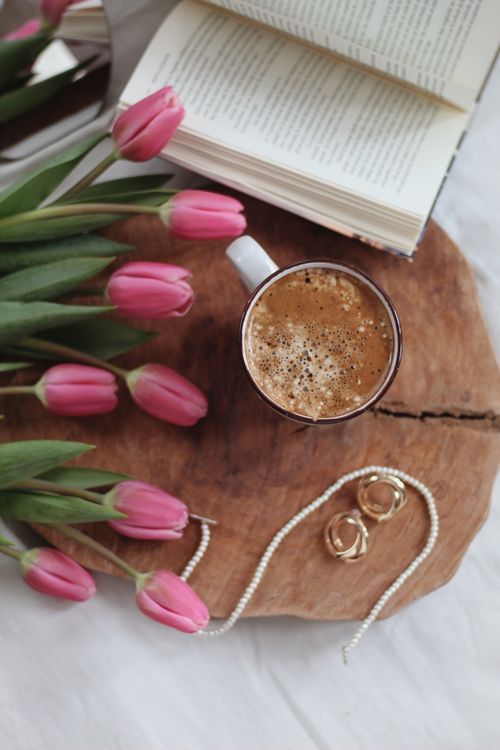 Free Flat lay of pink tulips, coffee, and book on wooden tray with jewelry. Stock Photo