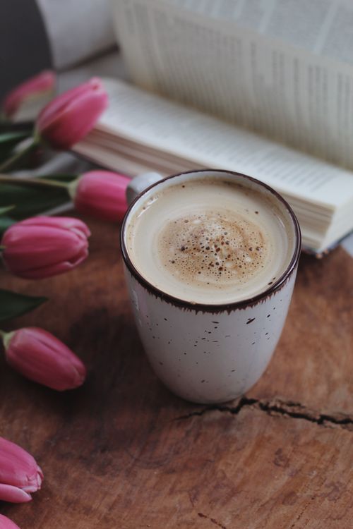 Free A relaxing coffee setup with pink tulips and an open book on a wooden surface. Stock Photo