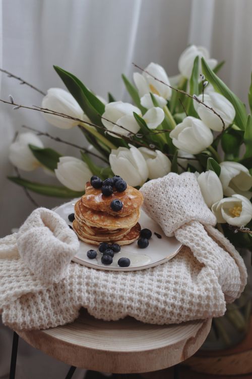 Free A cozy breakfast setting with pancakes topped with blueberries and fresh tulips. Stock Photo