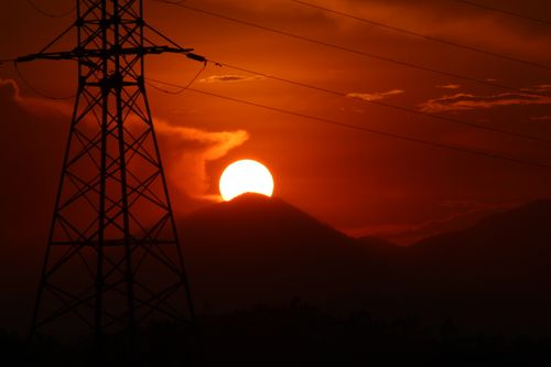Free Dramatic sunset with a silhouette of a transmission tower against an orange sky. Stock Photo
