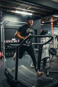 Adult male exercising on a treadmill in a modern indoor gym with various equipment.