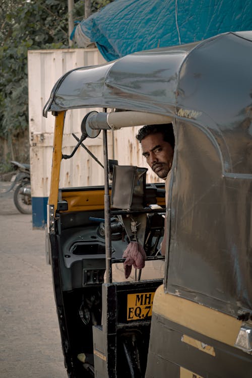 Free Man in Brown Jacket Sitting on Yellow and Black Auto Rickshaw Stock Photo