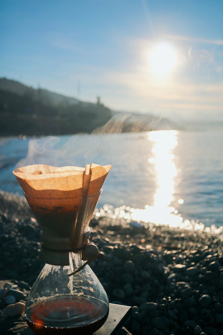 Turkish Coffee Brewing On Pebbles And Morning Sun Reflecting In The Sea