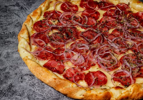 Close-up of a pepperoni pizza with onions on a textured surface in Rio de Janeiro, Brazil.