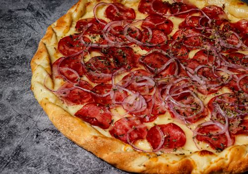 Free Close-up of a pepperoni pizza with onions on a textured surface in Rio de Janeiro, Brazil. Stock Photo
