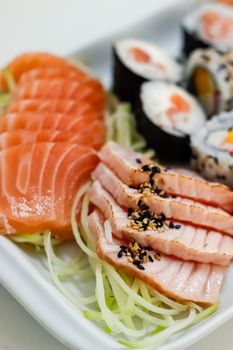 Appetizing close-up of sashimi and sushi rolls with salmon and sesame seeds.