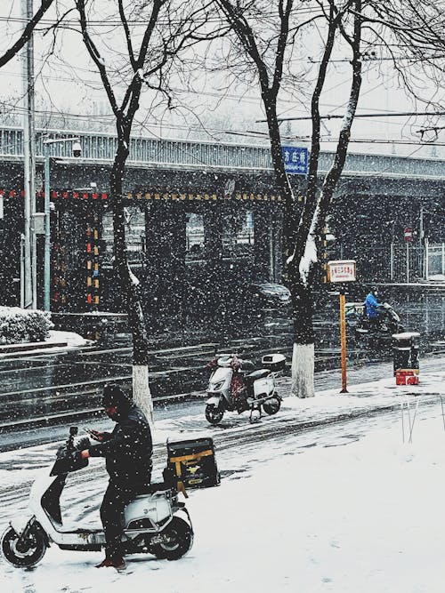 Man Riding on a Scooter Motorcycle during Snowy