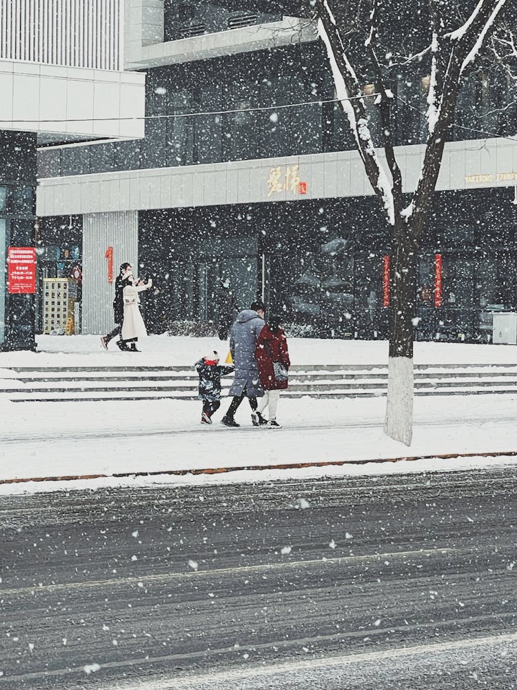 A Family Walking On A Sidewalk During Winter