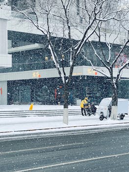 A delivery person navigates a snowy city street, capturing the essence of winter in urban life.