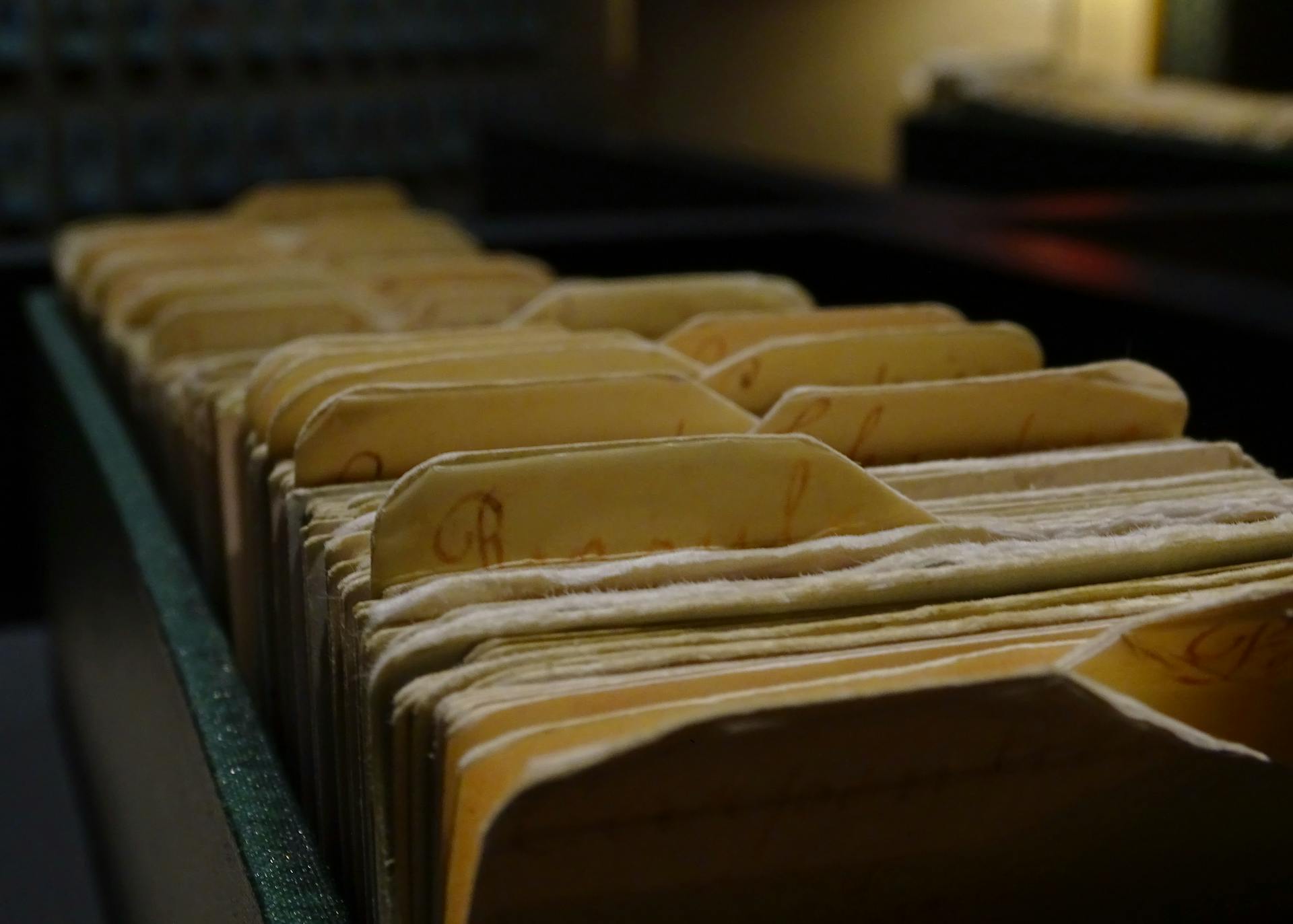 Vintage file folders organized in a row inside a dimly lit room.