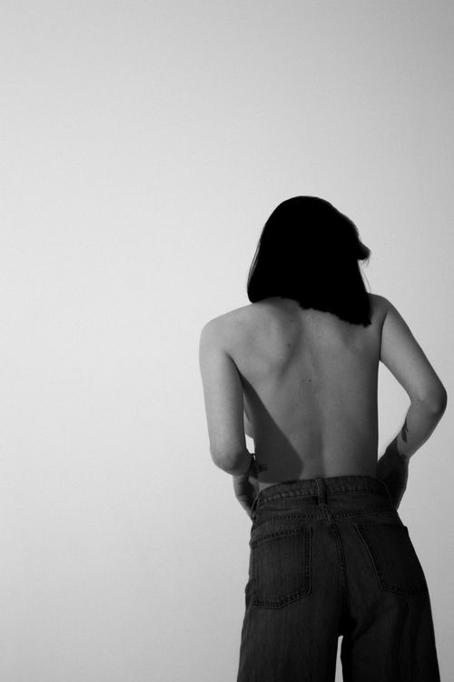 Free Artistic black and white portrait showing woman's back with denim jeans in minimal setting. Stock Photo