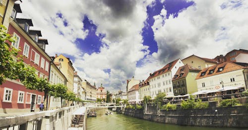 River Near Building Under White Grey and Blue Sky during Dayime