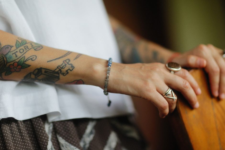 Tattooed arm adorned with rings and a bracelet, showcasing artistic body art and fashion.