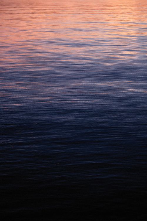 Free A calming view of the ocean's surface during twilight with soft colors reflecting on the water. Stock Photo