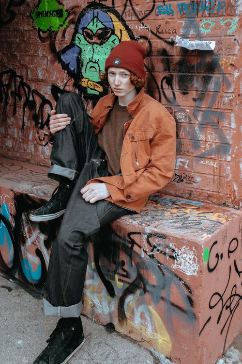 Free Redhead teenager in hip fashion posing against colorful graffiti wall. Stock Photo