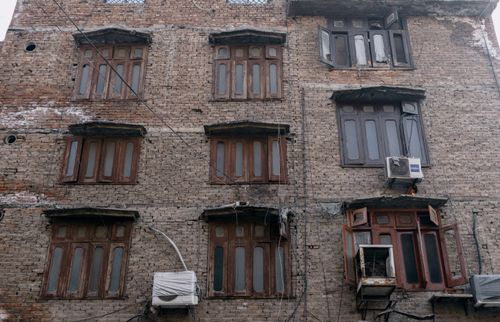 Free A rustic brick building with wooden-framed windows and air conditioners in Faisalabad. Stock Photo