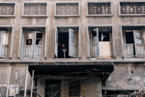 Men Looking Out Broken Windows of a Building
