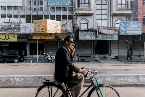 An Elderly Man Riding a Bicycle while Strolling on the Street