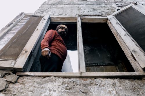 Free A man gazes out from a wooden window in an urban area, capturing a unique perspective. Stock Photo