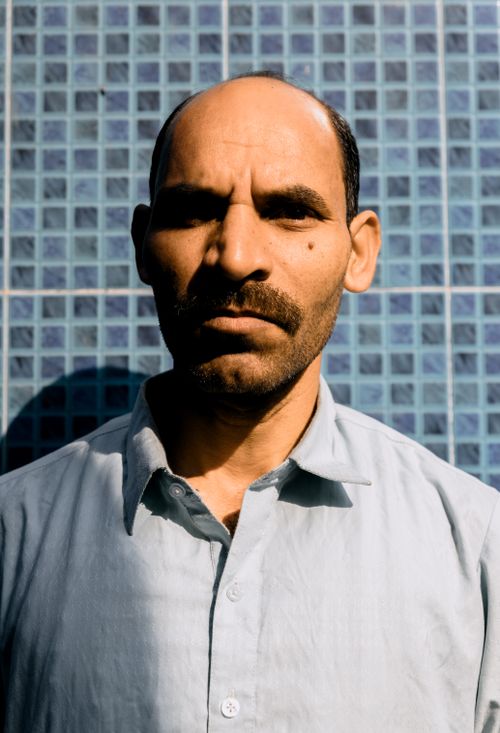 Free Portrait of a serious looking man in a button down shirt against a blue tiled wall in Faisalabad, Pakistan. Stock Photo