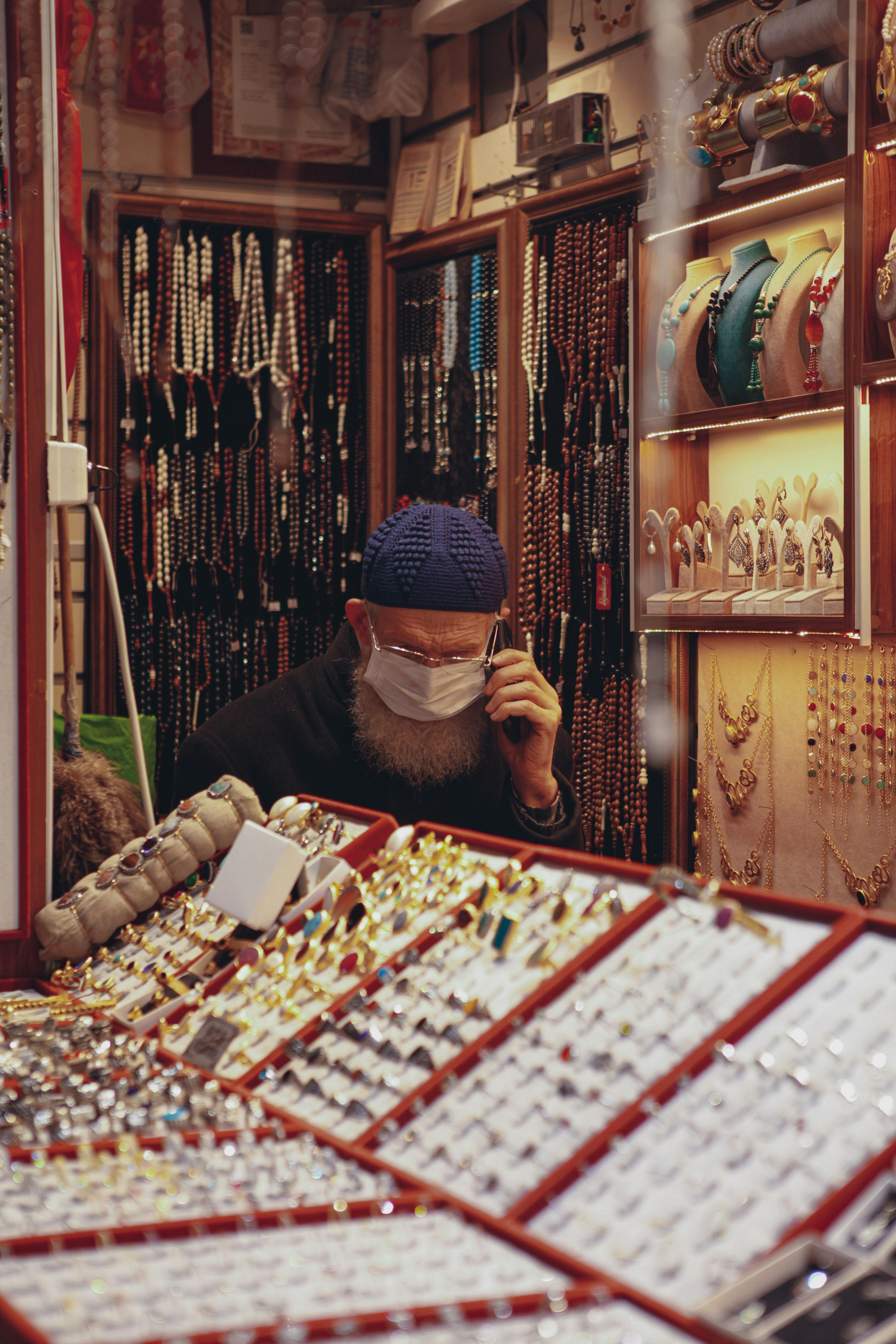 salesman in jewellery shop sitting at counter and talking on mobile phone