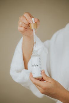 Close-up of a person holding a skincare serum bottle with a dropper, ideal for beauty and wellness themes.
