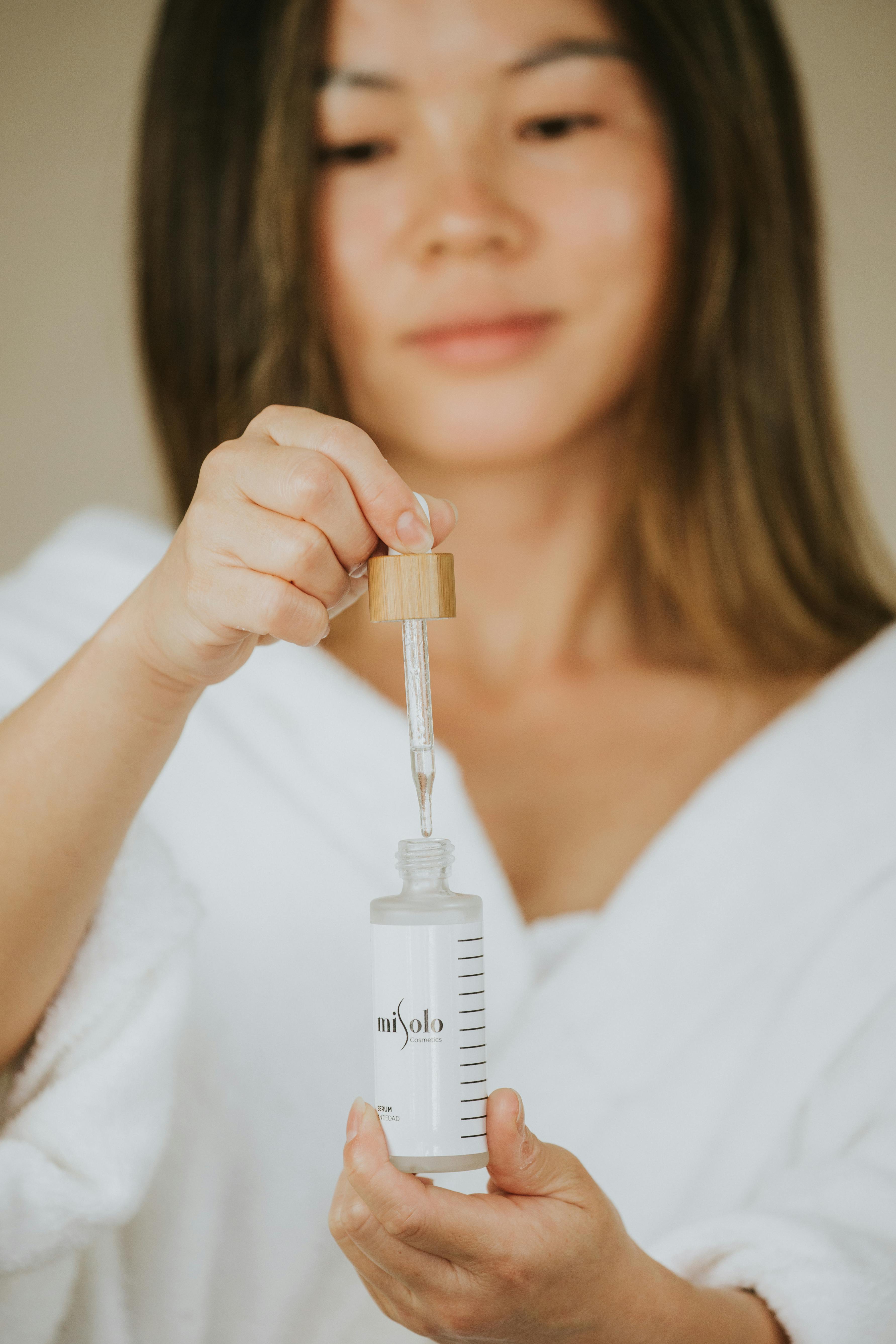 A Woman Using a Dropper Bottle · Free Stock Photo