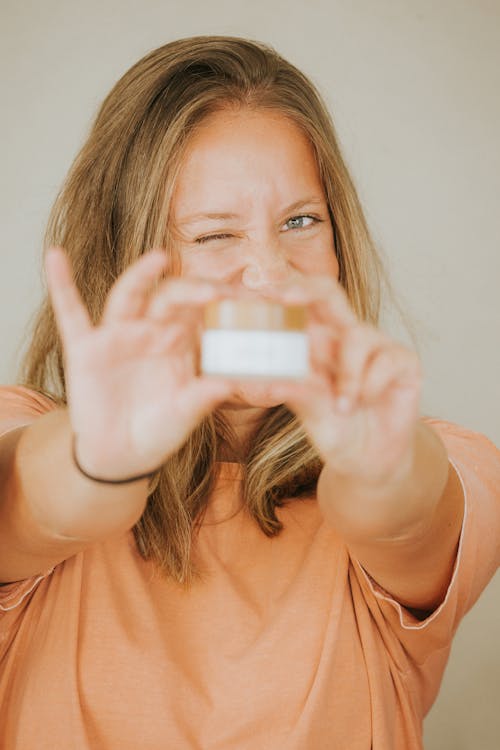 Woman Holding a Round Container while Winking at the Camera