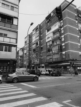 Monochrome view of a busy city street with buildings and parked cars.